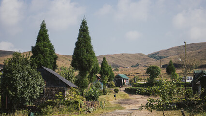 Obraz premium Rural scene with houses and trees in a hilly area during daytime under a clear sky