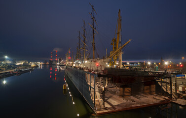 three-masted sailing ship in dry dock during repairs at the shipyard