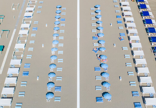 Aerial view of neat rows of beach umbrellas and cabanas create a symmetrical pattern on the sandy shore, Forte dei Marmi, Tuscany, Italy.