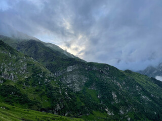 Fototapeta premium Fog and clouds cover mountains at dusk in the countryside during the summer season