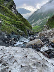 Obraz premium Mountains and stream flow through rocky landscape in high altitude area during cloudy weather