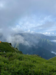 Obraz premium Hikers taking rest near green hills and misty mountains at dawn after a long trek in quiet nature