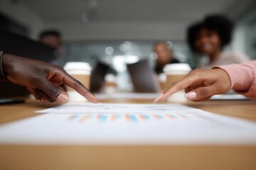 Business colleagues hands pointing at charts and graphs during a corporate meeting