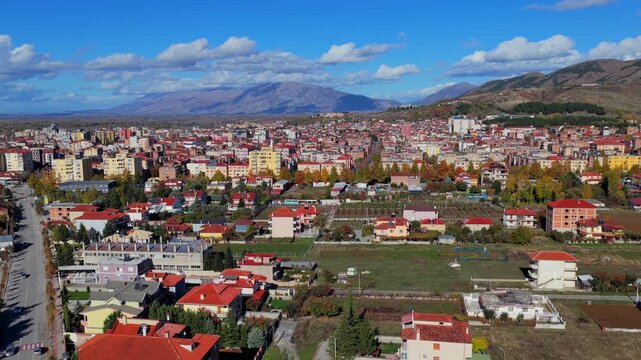 Aerial video of Kor&ccedil;&euml; in autumn, showing the city&rsquo;s dense neighbourhoods framed by open fields and distant mountain ranges.