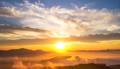 A breathtaking sunrise illuminates the horizon, casting warm hues over the misty mountains