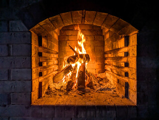 Baking of food in wood-fired oven on village or local street market. Firewood with fire creates light that fills the large volume of the brazier