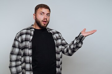 Man in plaid shirt gestures with surprise in a simple indoor setting during the day