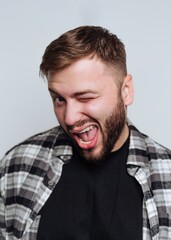 Fototapeta premium Man makes a playful expression while winking with a smile in a casual setting
