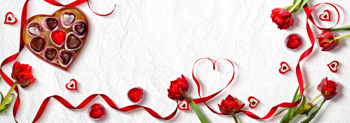 Valentine's Day Celebration with Tulips, Heart Chocolates, and Red Ribbons on White Background, banner