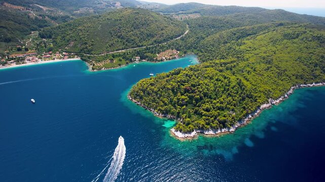 High angle aerial view of Panormos Bay and Blo harbor on Skopelos island, Greece. Turquoise sea water with sailing and speed boats among lush green hills 