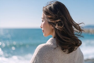 Woman looking at sea in cozy sweater on sunny day