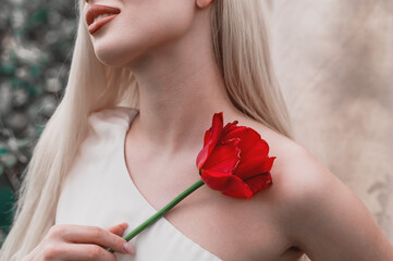 A blonde girl with long hair holding a bouquet of pink tulips against a light textured background. Happy International Women's Day, the first day of spring, Mother's Day, and spring holiday.
