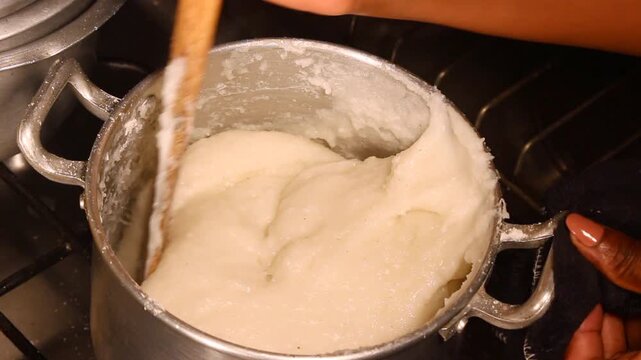 Stirring Maize and Cassava Flour on a Charcoal Stove to Prepare Traditional African Staple Food Known as Ugali, Nshima, Sadza, or Xima