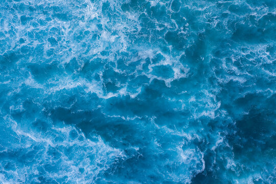 Aerial view of the turquoise ocean's surface, a mesmerizing dance of light and foam creating a symphony of textures and tones, Great Ocean Road, Lorne, Victoria, Australia.
