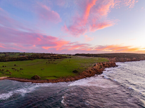 Aerial view of rugged cliffs meet the crashing waves under a vibrant sunset sky painted with pastel hues, Second Valley, South Australia, Australia.