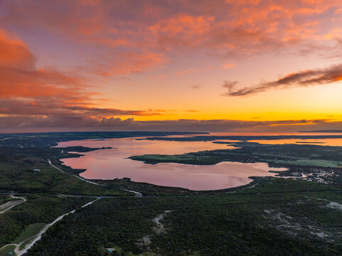Aerial view of the tranquil lagoon reflecting the vibrant hues of the sunset, casting a golden glow over the surrounding landscape, Coorong, South Australia, Australia.
