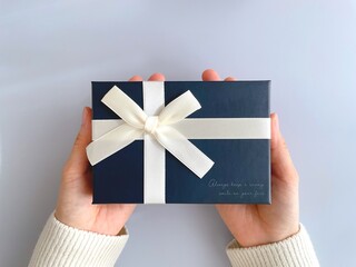 Woman's hand holding a gift on light blue background