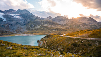 A serene evening at Lago Bianco showcases the beauty of the Swiss Alps. The sun sets behind...