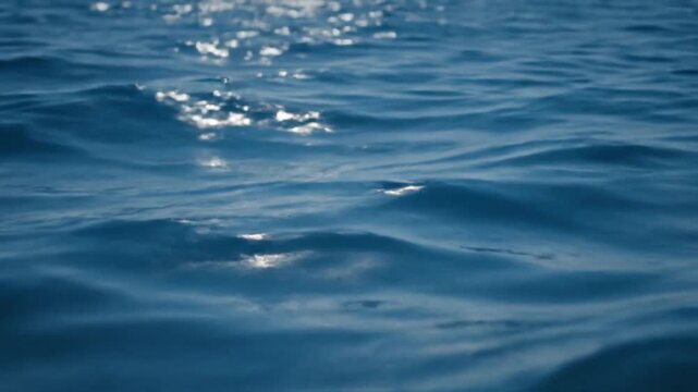 Gentle waves on a calm ocean surface with sunlight reflecting on ripples with serene and peaceful and tranquil and nature and marine and relaxation
