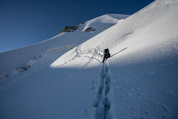A climber ascends the snowy slopes of Piz Palu in the Swiss Alps, making progress toward the summit...