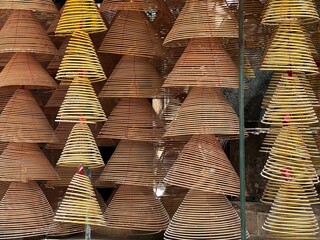 Numerous large, conical spiral incense coils hanging from a ceiling, in the A-Ma Temple in Macau