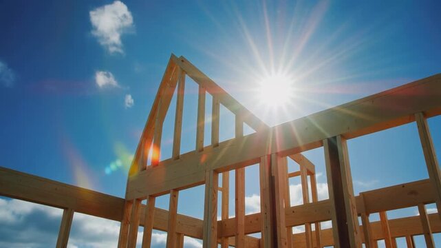 Sun shining through house framing under construction, building progress footage.