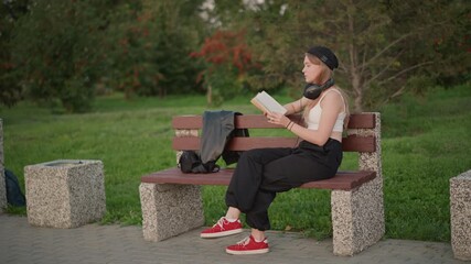 Woman deeply engaged with book outside, Female student intently concentrating on studying at sunny park, Young lady focused on her academic reading while seated outdoors in sunlit park area