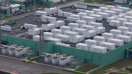 Aerial view of a vast, geometric expanse of white containers atop a green building, stark against the grey landscape, Middenmeer, Netherlands.