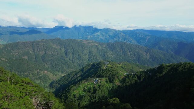 High forward aerial gliding over the scenic mountain highway and vast, tiered rice terraces under clear blue skies in Atok, Benguet, Philippines.