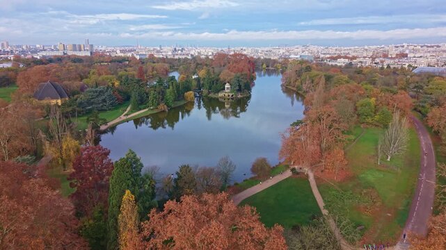 Aerial drone view of &Icirc;le de Reuilly and the Temple of Love in Bois de Vincennes. The colorful autumn park and lake contrast with the Paris skyline, France