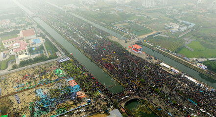 Dhaka, Bangladesh - 25 December 2025: Aerial view of a vast gathering along the Purbachal Expressway, a sea of people and vibrant colors contrasts with the still waters.