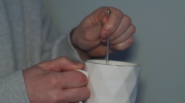 A close-up of a beautiful cup with a hot drink inside.
A person stirs tea in a glass with a teaspoon.