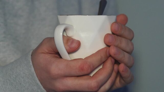A close-up of a beautiful cup with a hot drink inside.
A person stirs tea in a glass with a teaspoon.