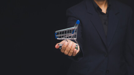 Businessperson holding mini shopping cart for online shopping concept