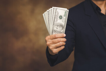 Businessperson holding US dollar banknotes with copy space