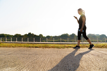 Woman walking outdoors after workout and using smartphone for virtual fitness assistant