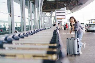 Asian woman traveler with luggage waiting at airport terminal