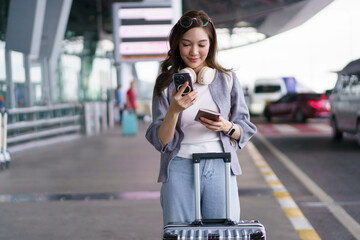 Asian woman traveler using smartphone with luggage at airport terminal