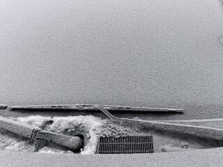 Frost-covered frozen car windshield, frozen wiper blades