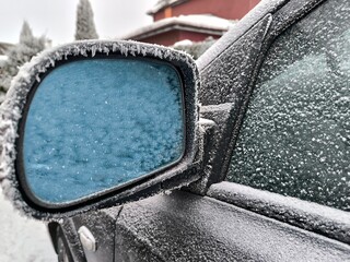 Frozen car side mirror covered in frost
