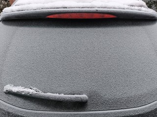 Frozen, frost-covered car rear window and windshield wipers