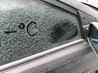 Minus degrees Celsius written on the frozen side window of a car