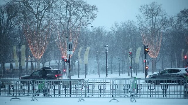 Pedestrians walk through heavy snowfall in Paris during winter. Decorative holiday lights are visible on trees, and people are dressed in warm winter clothing