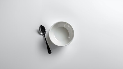 Closeup of a plain ceramic bowl and spoon from above, ideal for recipe or menu backgrounds