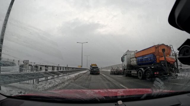 Traffic on a snowy road with trucks navigating in winter weather conditions