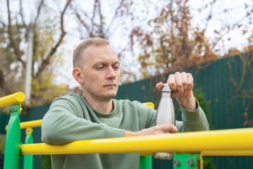 Man exercising outdoors taking a water break