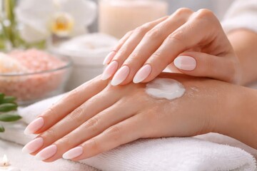 Naklejka premium Close up of elegant hands applying baby boomer nail art and skin spa treatment