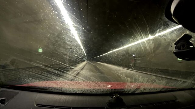 Driving through a snowy tunnel in winter at night with lights and road signs