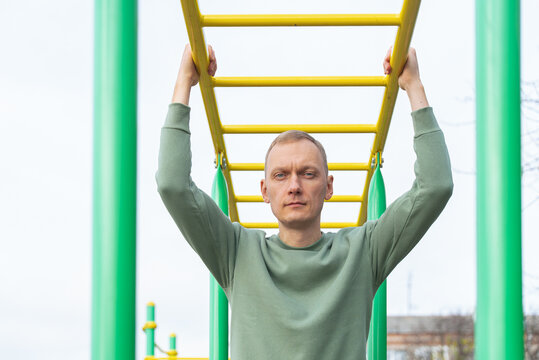 Man exercising on yellow monkey bars outdoors