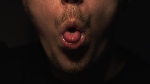 Close-up of tongue mimicry.
A man actively moves his tongue in his mouth.
Facial expressions and mouth gestures.
Tongue, funny, moving, body parts, face